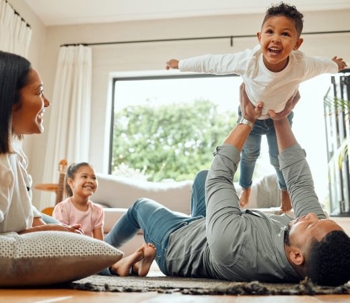 a child is held up in the air with family